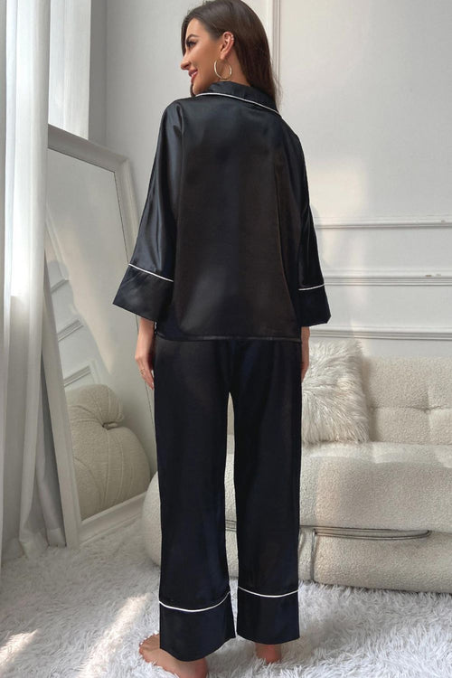 Black satin button-up pajama top with contrast piping and matching wide-leg pants