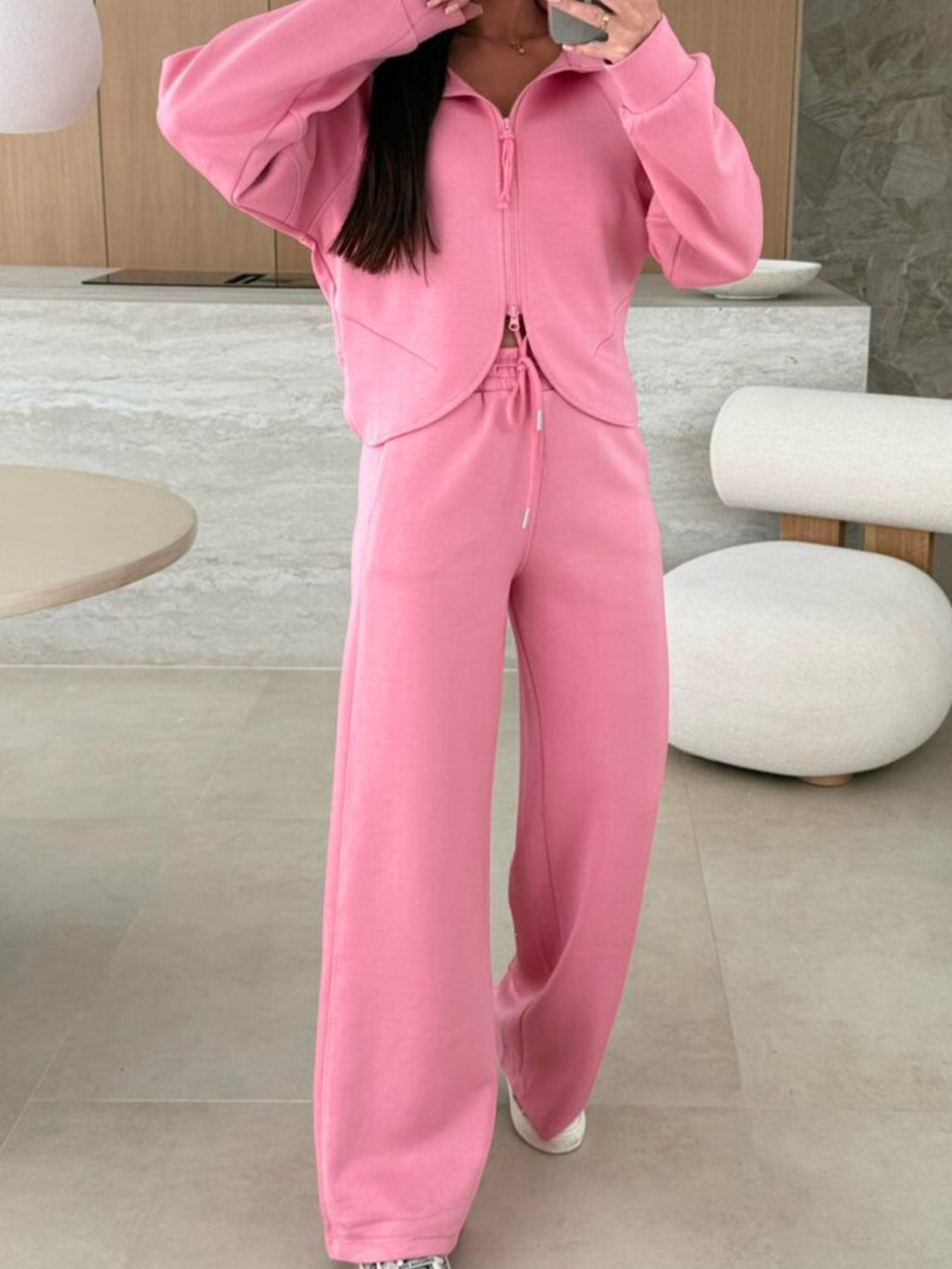 Dusty pink zip-up hoodie and drawstring wide-leg loungewear set, worn with hand raised to hair