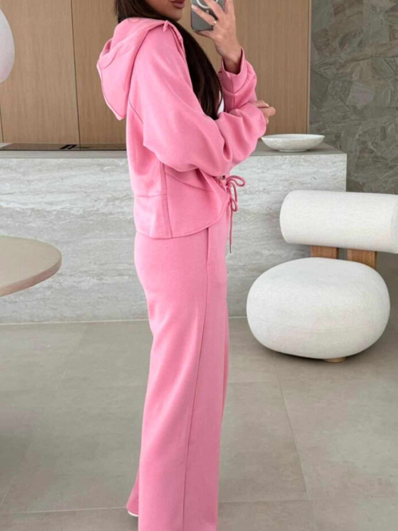 Dusty pink zip-up hoodie and drawstring wide-leg loungewear set, worn with hand raised to hair