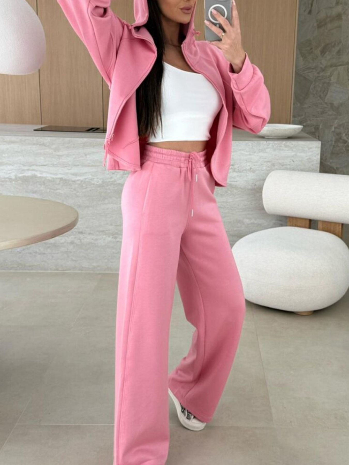 Dusty pink zip-up hoodie and drawstring wide-leg loungewear set, worn with hand raised to hair