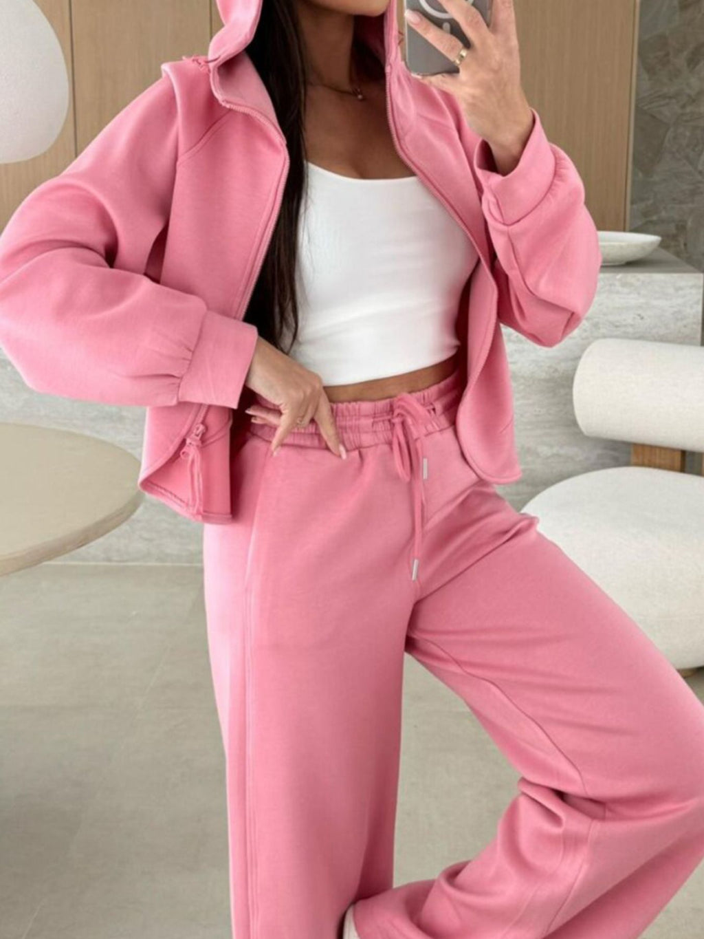 Dusty pink zip-up hoodie and drawstring wide-leg loungewear set, worn with hand raised to hair