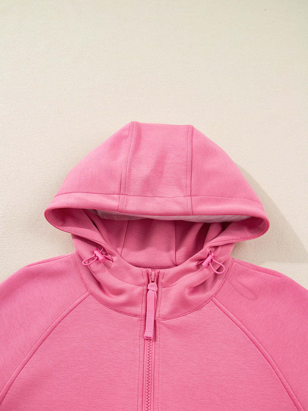 Dusty pink zip-up hoodie and drawstring wide-leg loungewear set, worn with hand raised to hair