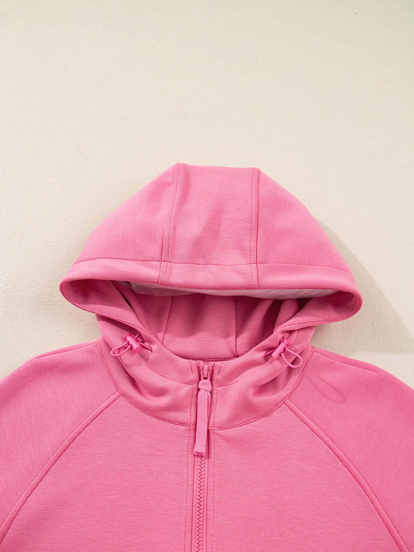 Dusty pink zip-up hoodie and drawstring wide-leg loungewear set, worn with hand raised to hair
