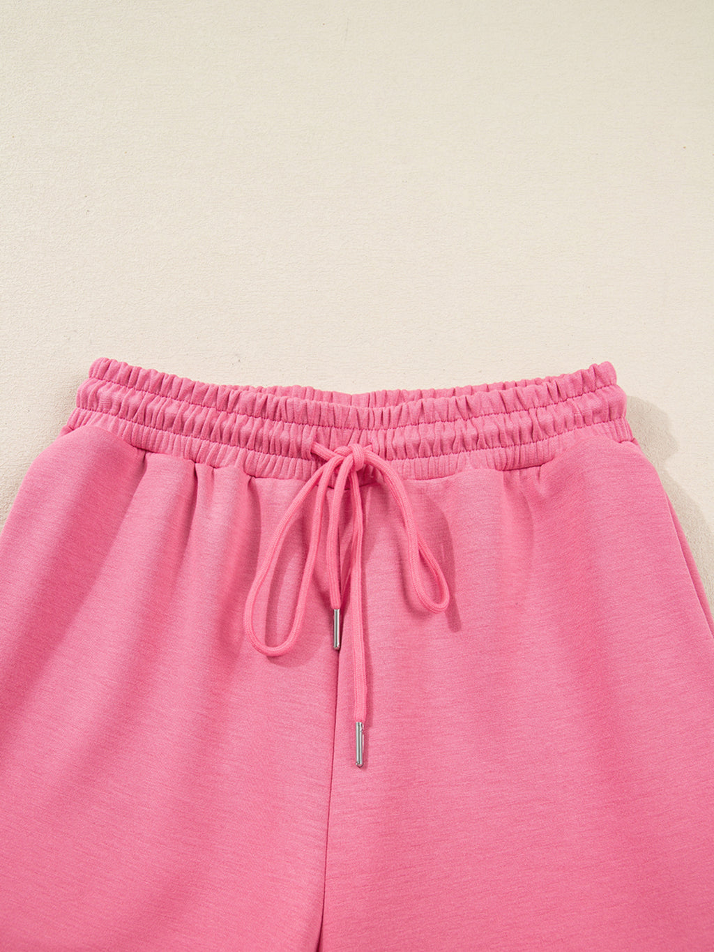 Dusty pink zip-up hoodie and drawstring wide-leg loungewear set, worn with hand raised to hair