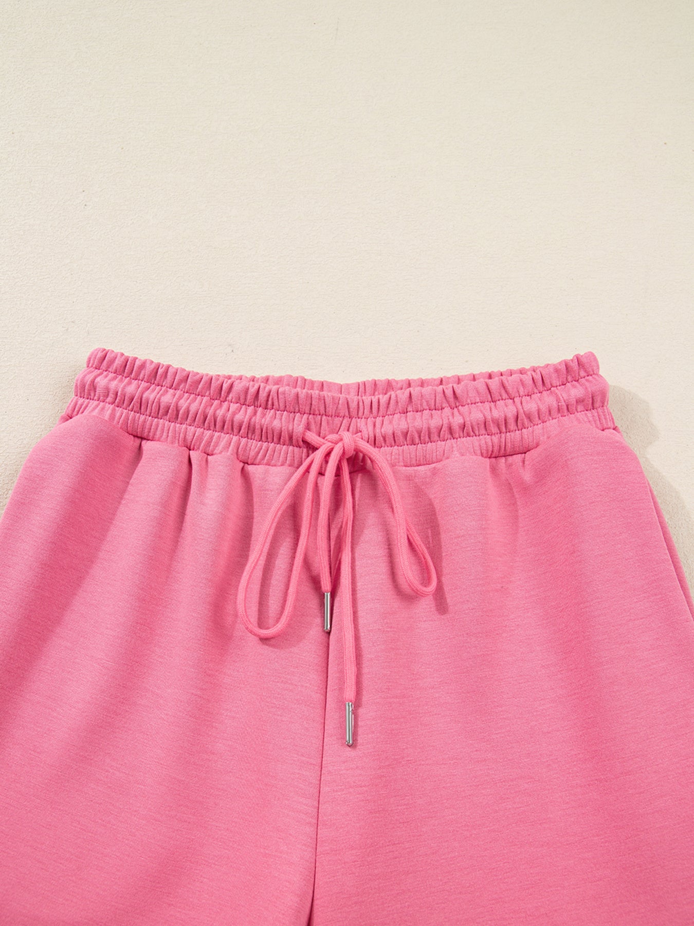 Dusty pink zip-up hoodie and drawstring wide-leg loungewear set, worn with hand raised to hair
