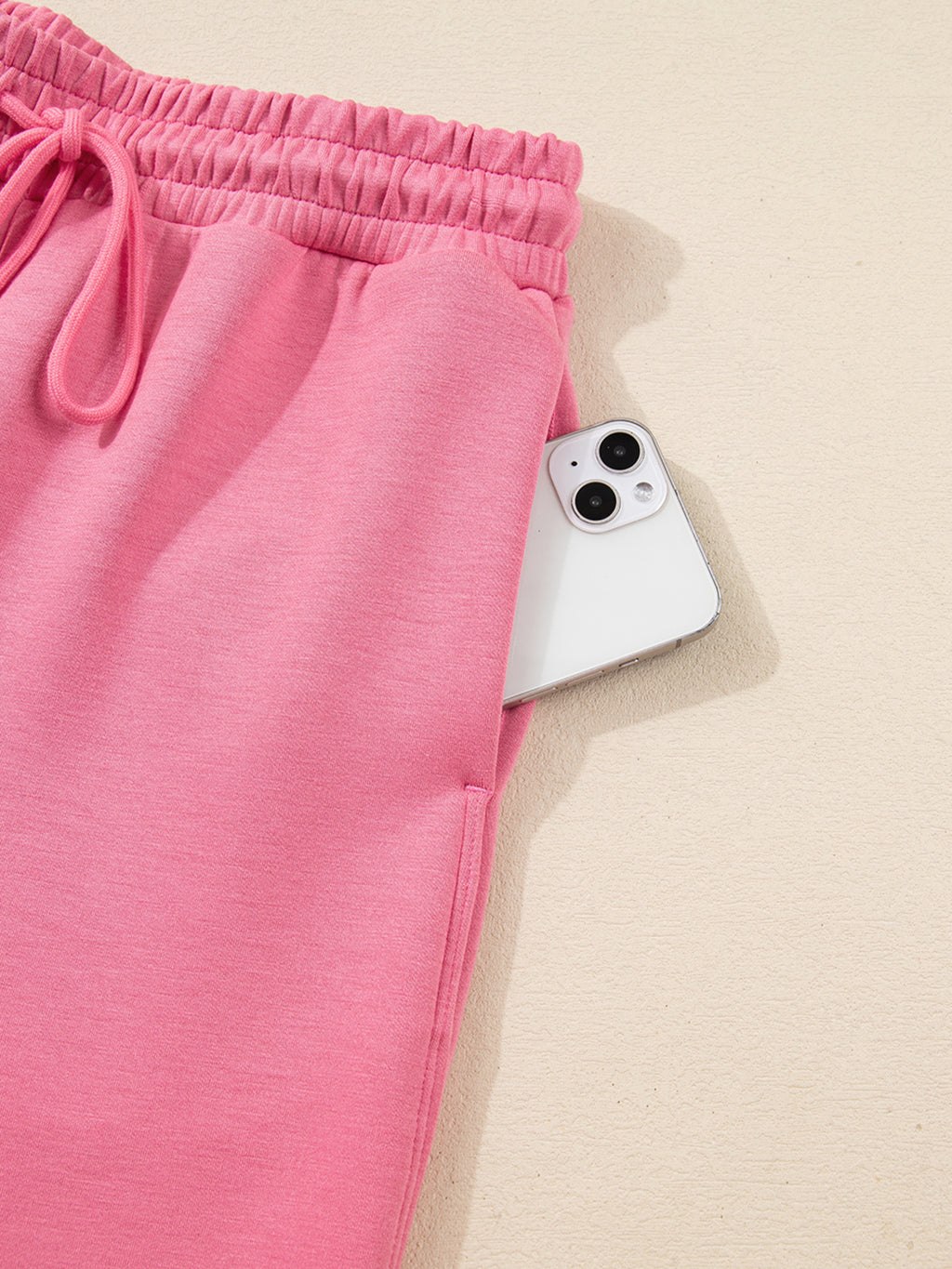 Dusty pink zip-up hoodie and drawstring wide-leg loungewear set, worn with hand raised to hair