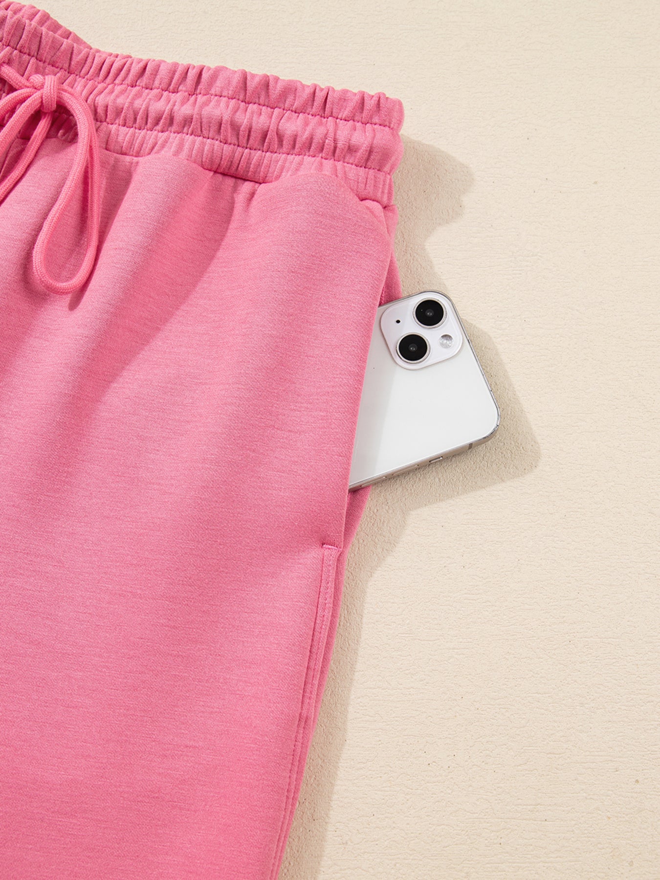 Dusty pink zip-up hoodie and drawstring wide-leg loungewear set, worn with hand raised to hair